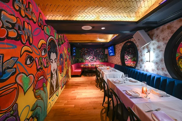A long dinner table beside the graffiti mural wall in the Graffiti Room at Sei Less