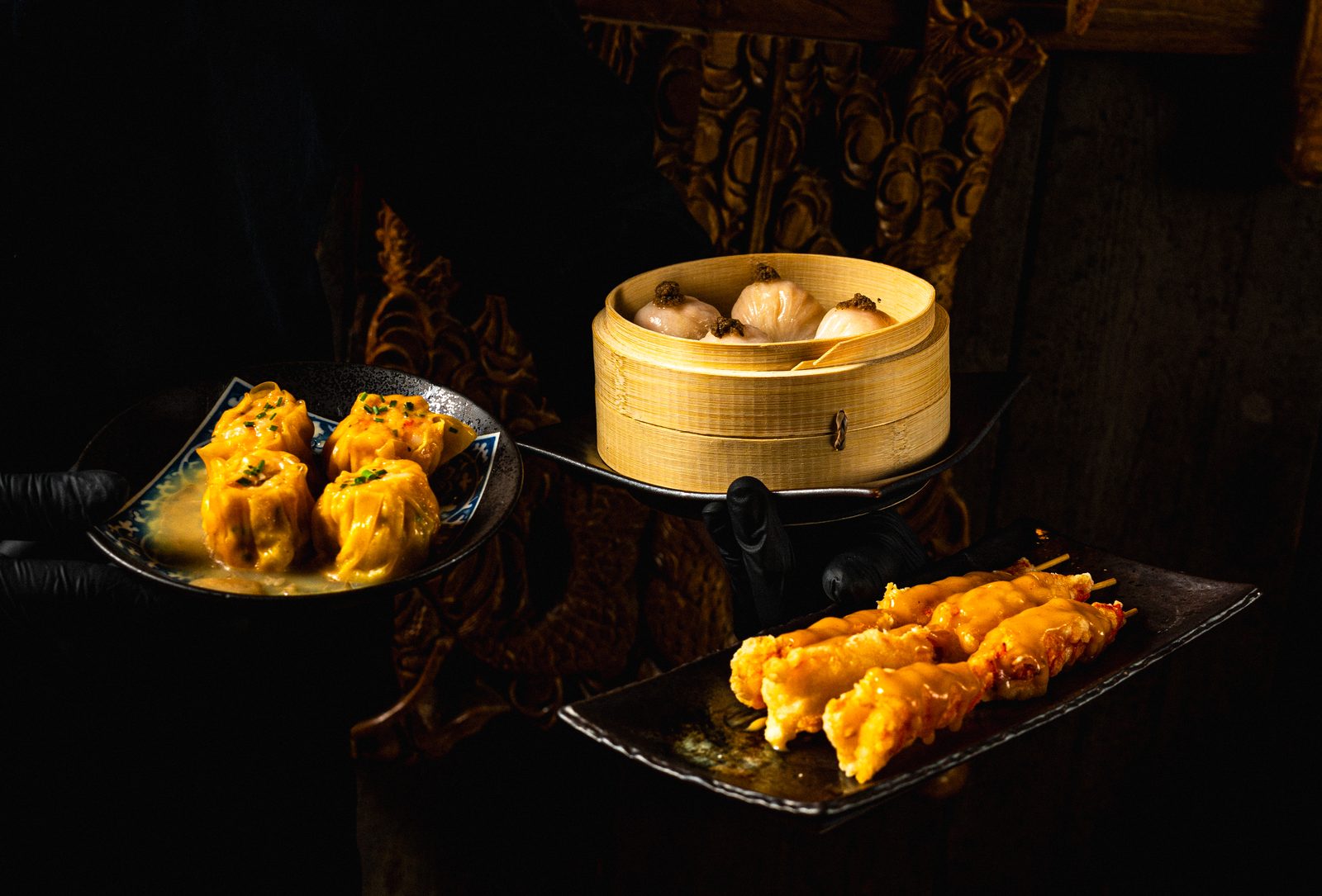 Sei Less dumplings, satay and crispy shrimp presented together by a server