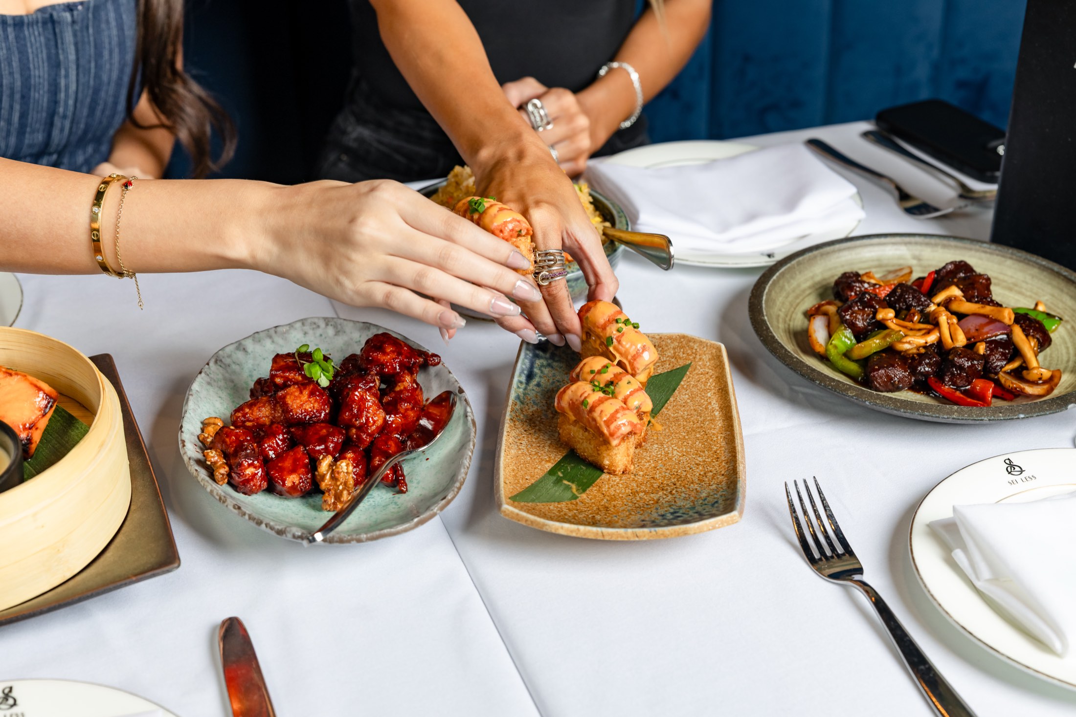 Small plates for NYC Restaurant Week at Sei Less — crispy chicken, spicy tuna crispy rice and wok-fried beef on a white-linen table in Midtown Manhattan